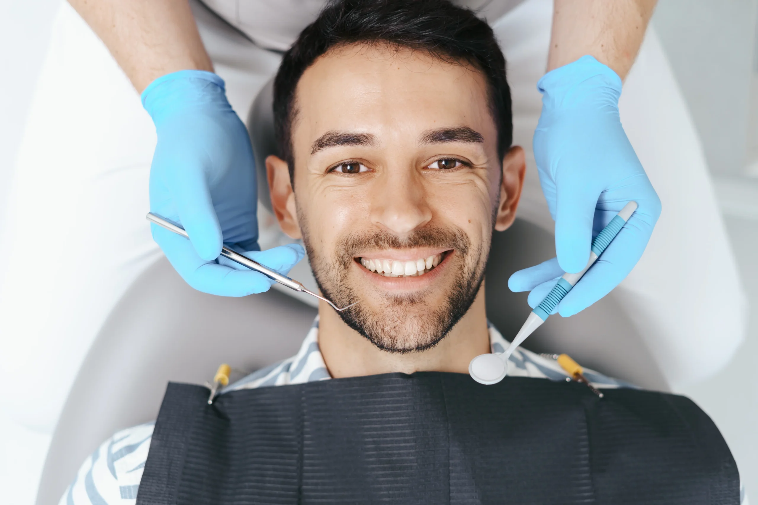 Hombre tumbado en el dentista sonriendo